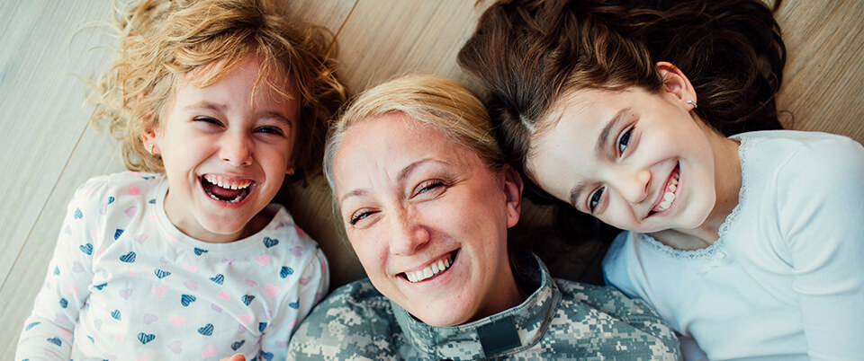 smiling mother lying on the floor with her happy daughters